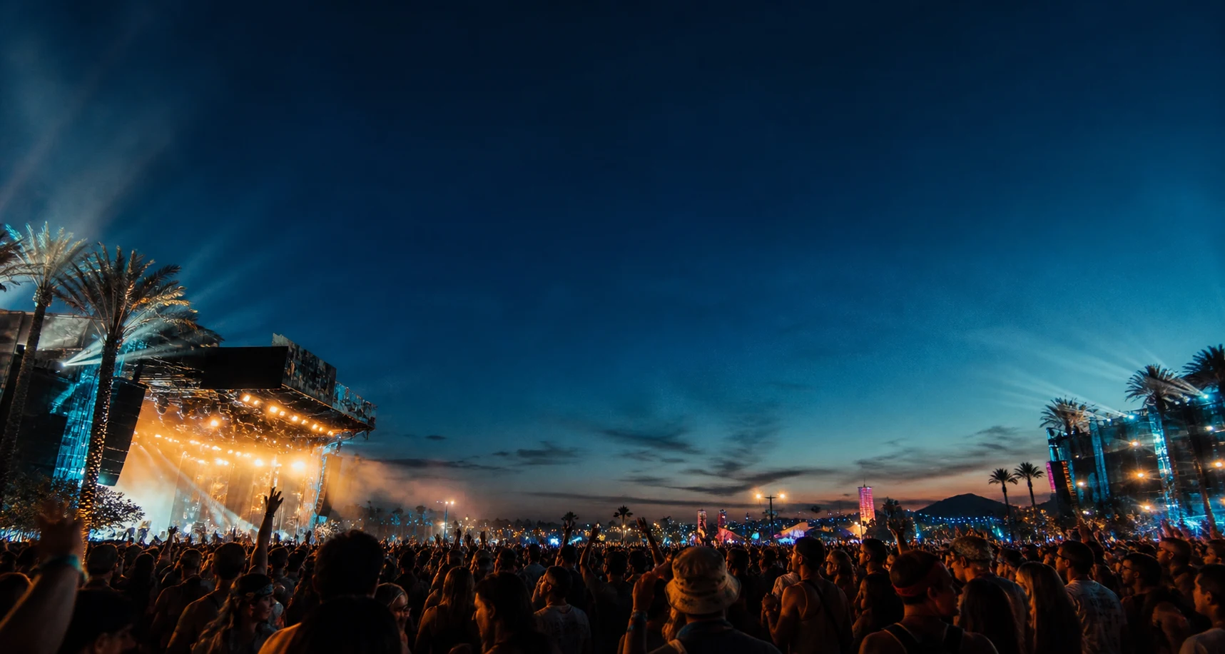 Festivalpublikum vor beleuchteten Bühnen in der Abenddämmerung